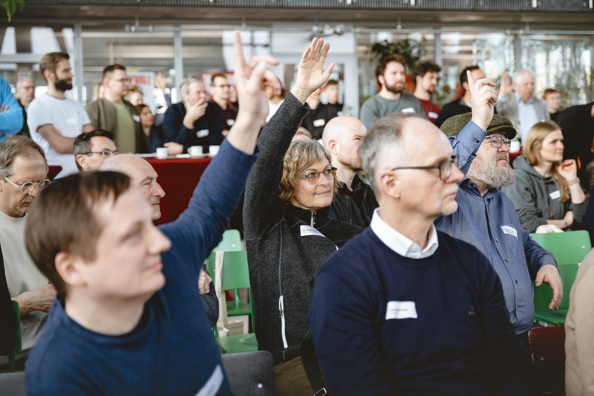 Mehrere Personen stimmen für Sessions ab, indem sie die die Hände heben.